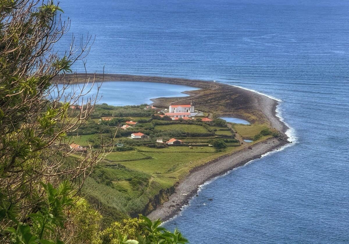 Scenic view of Fajã da Caldeira de Santo Cristo on São Jorge in the Azores, Portugal, with lush greenery, houses, and surrounding ocean waters