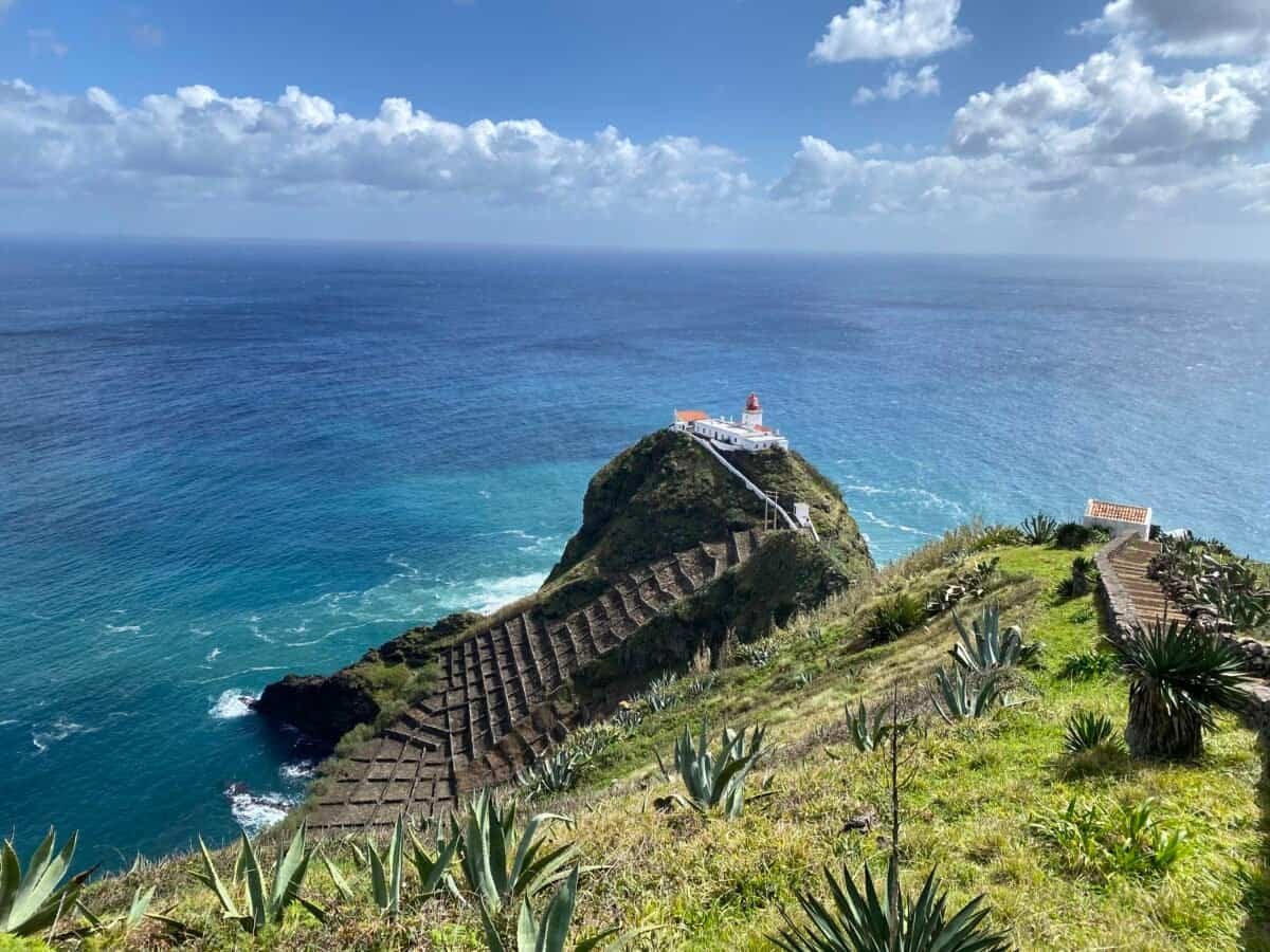Wide view of the Farol de Gonçalo Velho lighthouse on Santa Maria on a terraced hill with desert plants in the Azores