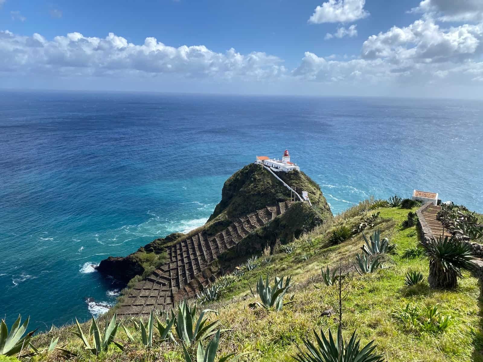 Wide view of the Farol de Gonçalo Velho lighthouse on Santa Maria on a terraced hill with desert plants in the Azores