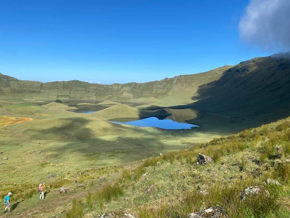 hikers exploring a volcanic caldera with a lake at the bottom on Corvo in the Azores