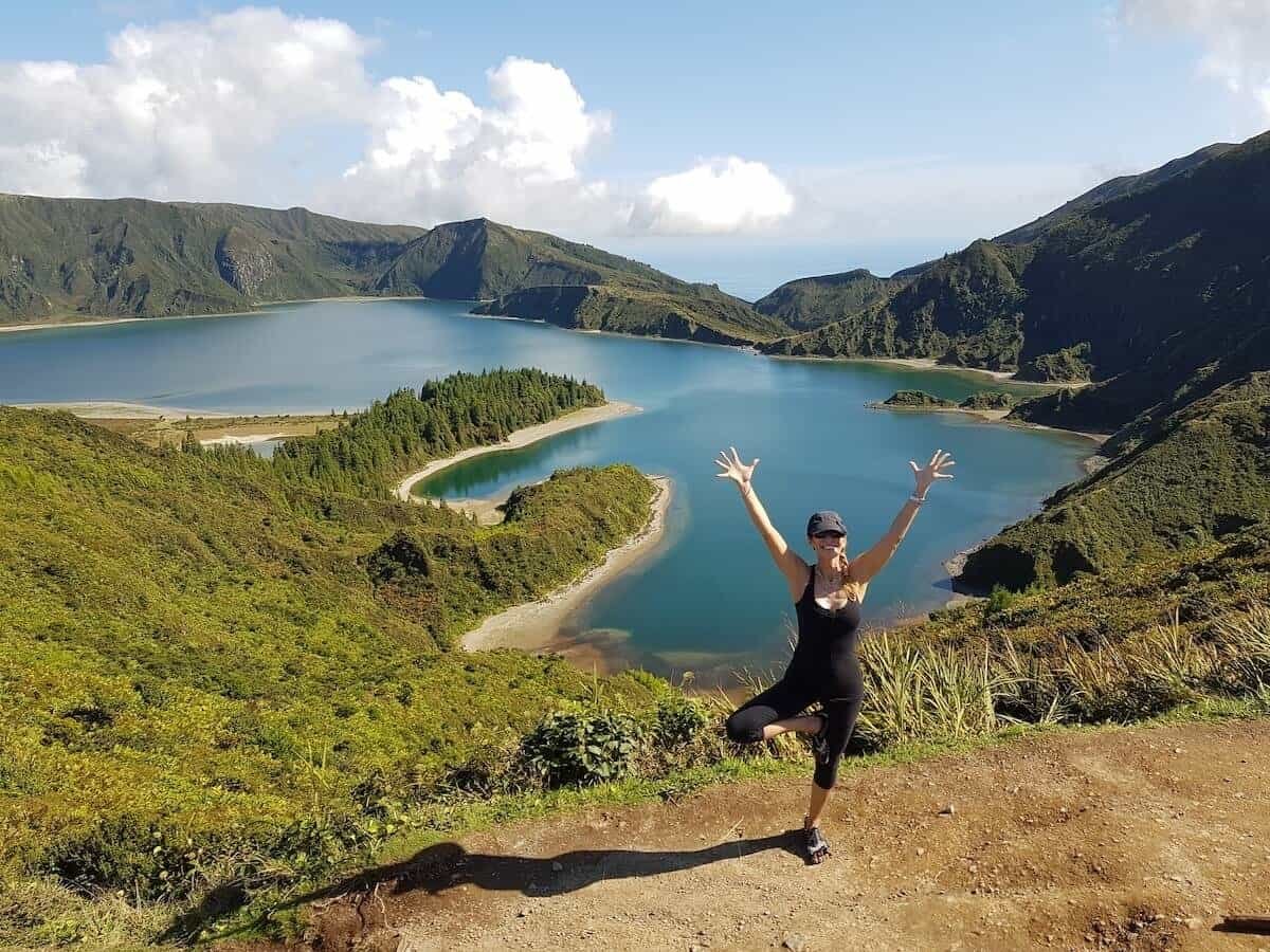 Woman standing above crater lake of Lago do Fogo on sunny day on São Miguel in the Azores