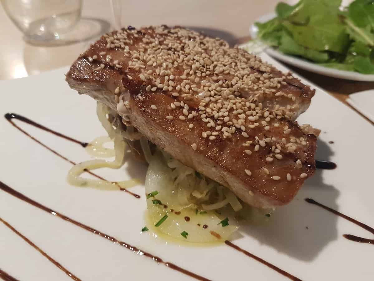 Grilled fish encrusted with sesame seeds on a decorative plate