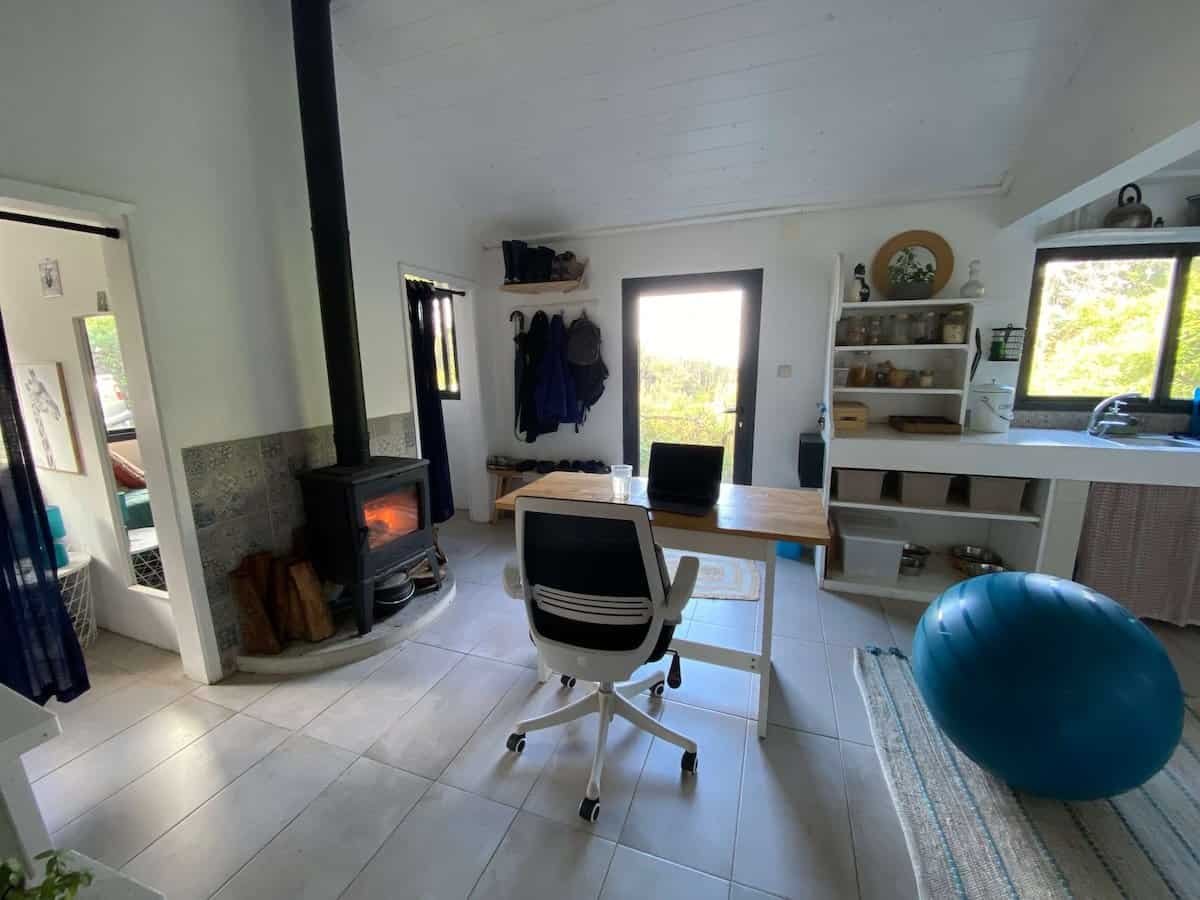 desk and office chair in front of wood-burning stove in a small cottage