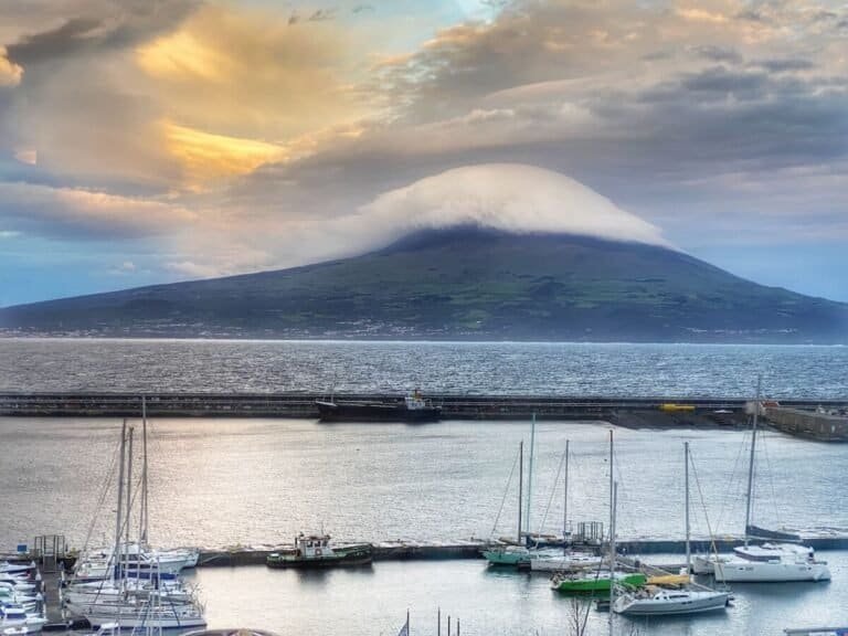 cloud-capped Pico Mountain overlooking Horta Bay and sailboats