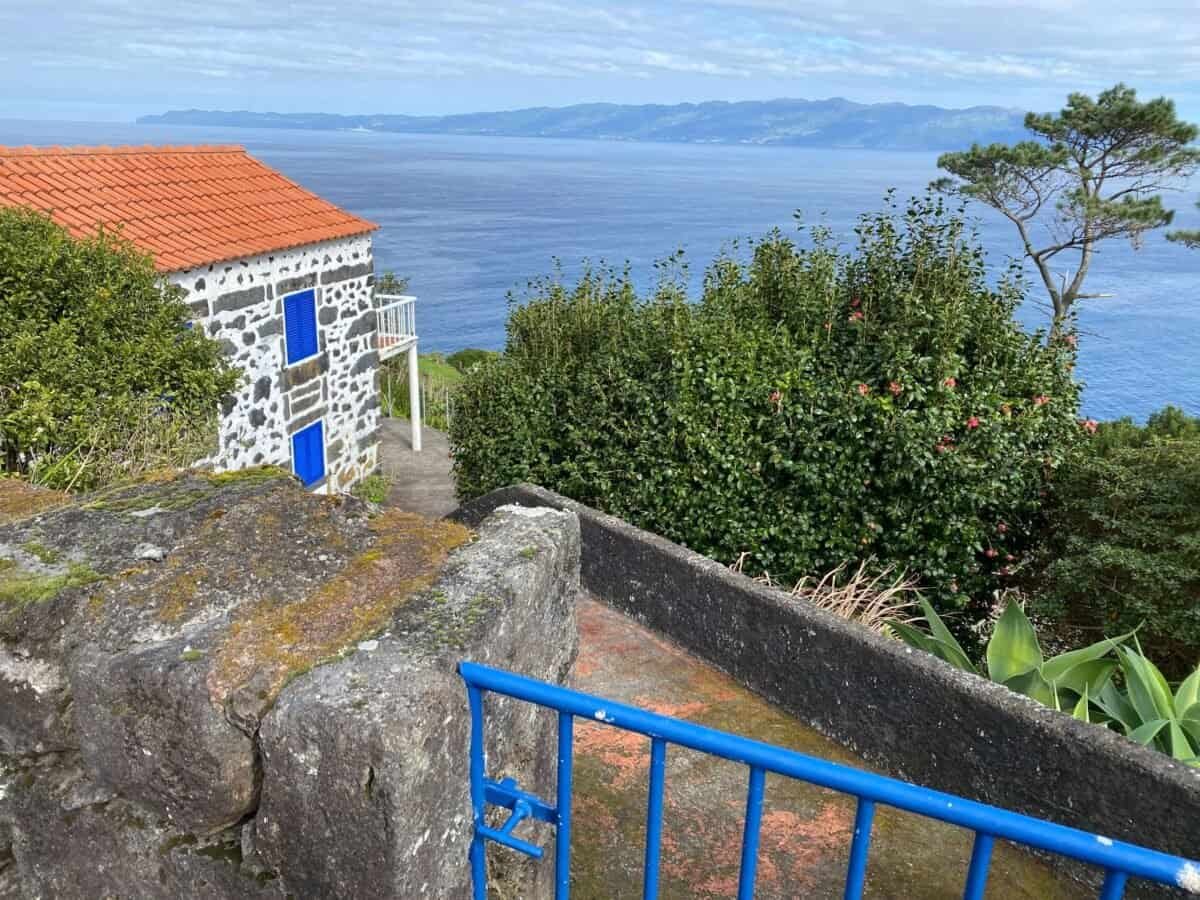 stone house with orange tile roof on a hillside overlooking the ocean on Pico Island in the Azores