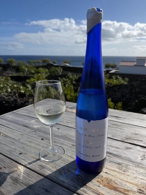 blue wine bottle and glass of white wine on wooden table at Adega Amaral on Pico Island in the Azores